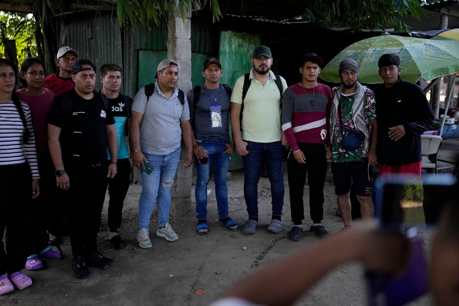 Venezuelan migrants stand in line to have their photo taken by a smuggler as proof that they paid the passage fee to cross from Tecun Uman, Guatemala to Tapachula, Mexico, Tuesday, Oct. 29, 2024. (AP Photo/Matias Delacroix)