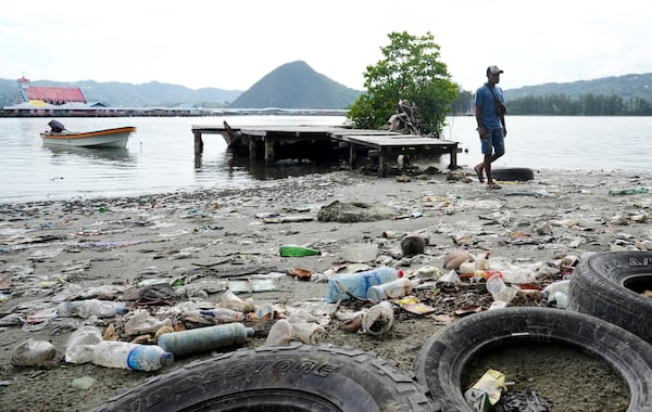 A man walks past plastic waste strewn along at Enggros village beach in Jayapura, Papua province, Indonesia on Wednesday, Oct. 2, 2024. (AP Photo/Firdia Lisnawati)