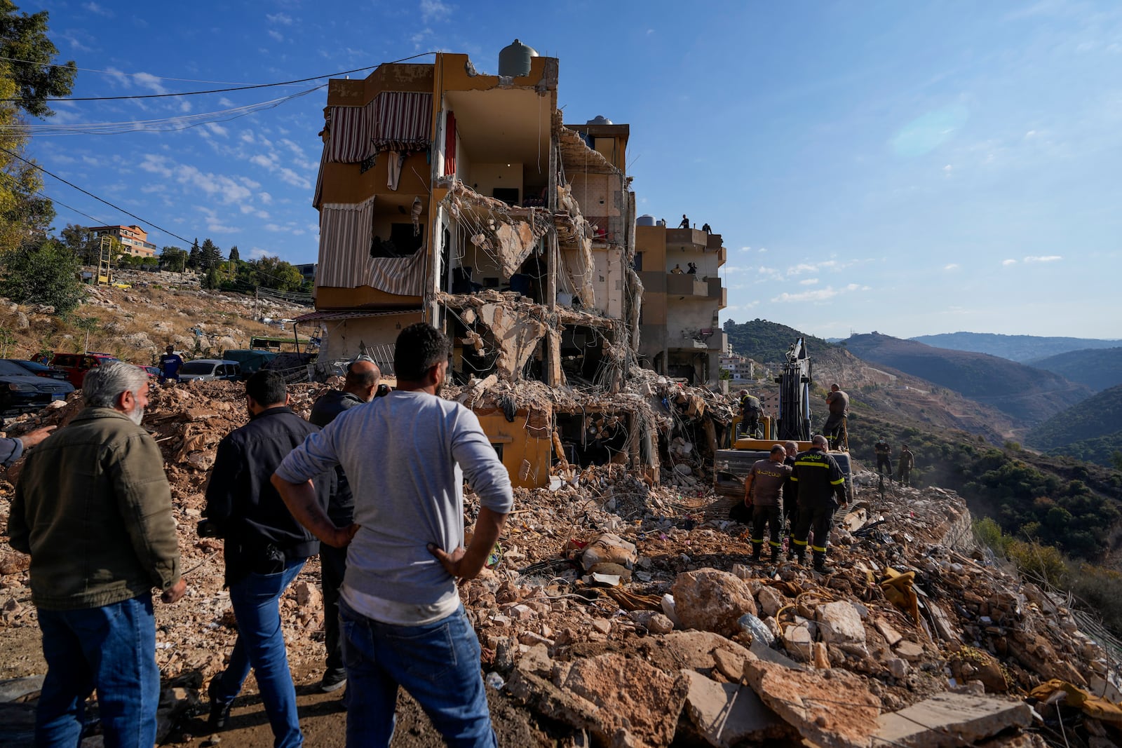 Rescue workers use an excavator to remove the rubble of a destroyed building hit in an Israeli airstrike on Tuesday night, as they search for victims in Barja, Lebanon, Wednesday, Nov. 6, 2024. (AP Photo/Hassan Ammar)