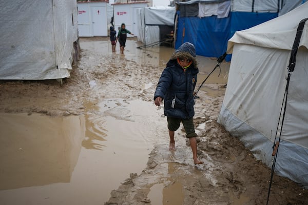 A boy walks barefoot through the mud after overnight rainfall at the refugee tent camp for displaced Palestinians in Deir al-Balah, central Gaza Strip, Tuesday, Dec. 31, 2024. (AP Photo/Abdel Kareem Hana)