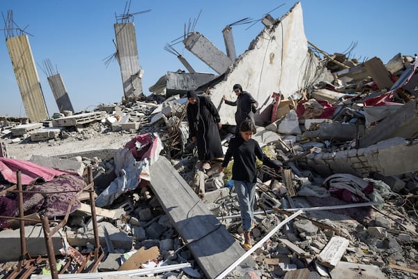 Members of the Abu Al Zamar family salvage items from under the rubble of their destroyed family home, in Rafah, southern Gaza Strip, Tuesday, Jan. 21, 2025, days after the ceasefire deal between Israel and Hamas came into effect. (AP Photo/Abdel Kareem Hana)