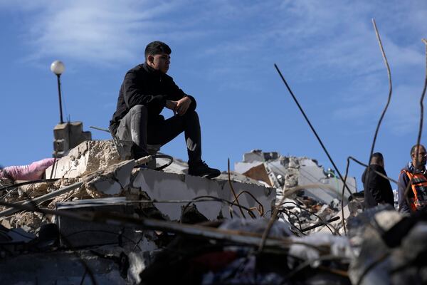 A Palestinian sits on the rubble at the site where Israeli forces killed two Palestinian militants who carried out a deadly attack on a bus in the West Bank earlier this month, in the West Bank village of Burqin, Thursday, Jan. 23, 2025. (AP Photo/Majdi Mohammed)