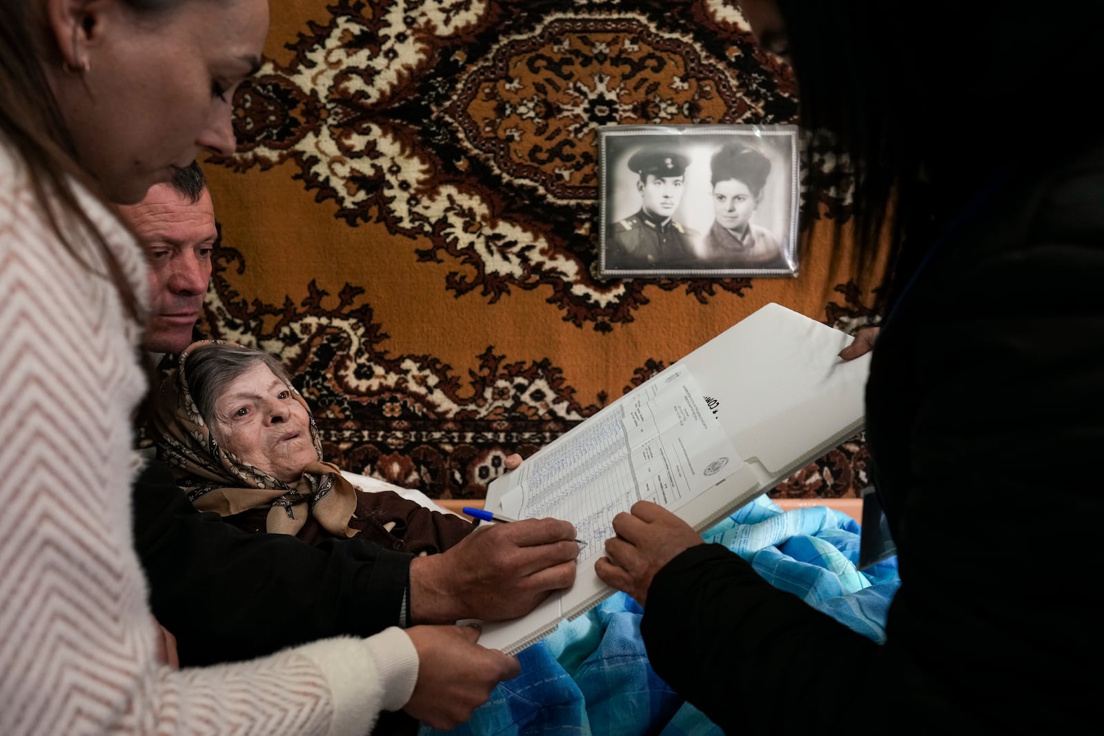 Tatiana, 78 years old, signs her name to receive a stamp to cast her vote in a mobile ballot box in the village of Hrusevo, Moldova, Sunday, Oct. 20, 2024, during a presidential election and a referendum on whether to enshrine in the Constitution the country's path to European Union membership. (AP Photo/Vadim Ghirda)