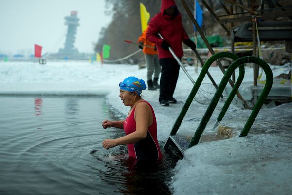 A woman reacts as she gets into a pool carved from ice on the frozen Songhua river in Harbin in northeastern China's Heilongjiang province, Tuesday, Jan. 7, 2025. (AP Photo/Andy Wong)