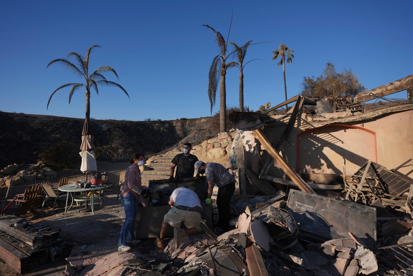 Heidi Nardoni, left, and family friends search her home destroyed by the Mountain Fire in Camarillo, Calif., Friday, Nov. 8, 2024. (AP Photo/Jae C. Hong)