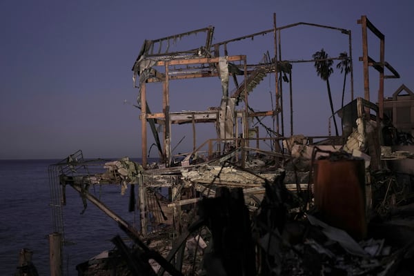 The sun rises behind a burned out home in Malibu, Calif., Tuesday, Jan. 14, 2025. (AP Photo/Carolyn Kaster)