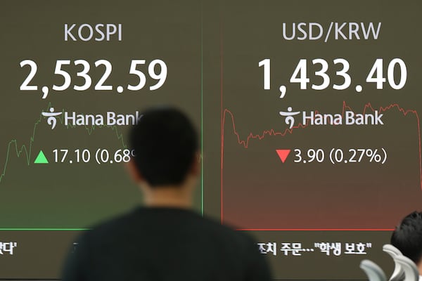 A currency trader walks by the screens showing the Korea Composite Stock Price Index (KOSPI), left, and the foreign exchange rate between U.S. dollar and South Korean won at a foreign exchange dealing room in Seoul, South Korea, Friday, Jan. 24, 2025. (AP Photo/Lee Jin-man)