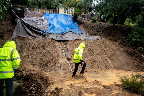 Permit Sonoma Director Tennis Wick crosses a mudslide to inspect a home as heavy rains fall near Healdsburg in unincorporated Sonoma County, Calif., Friday, Nov. 22, 2024. (AP Photo/Noah Berger)