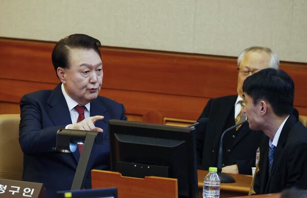 South Korea's impeached President Yoon Suk Yeol, left, speaks to his lawyers as he attends the fourth hearing of his impeachment trial over his short-lived imposition of martial law at the Constitutional Court in Seoul, South Korea, Jan.23, 2025. (Jeon Heon Kyun/Pool Photo via AP)