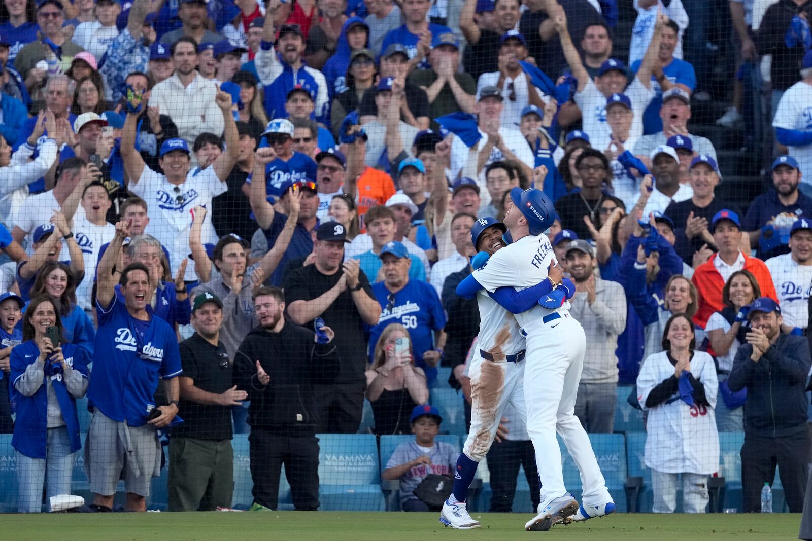 Los Angeles Dodgers' Freddie Freeman, right, and Mookie Betts celebrate after they scored on a single by Max Muncy during the first inning in Game 1 of a baseball NL Championship Series against the New York Mets, Sunday, Oct. 13, 2024, in Los Angeles. (AP Photo/Mark J. Terrill)