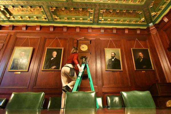 Bethany Gill climbs a ladder to wind a clock in a Pennsylvania Senate hearing chamber, Dec. 13, 2024, in Harrisburg, Pa. It's one of 273 clocks in Pennsylvania's ornate state Capitol complex buildings that must be wound by hand. (AP Photo/Marc Levy)