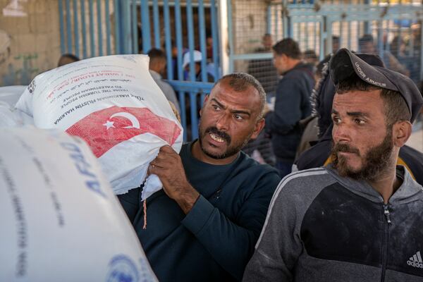 A man grabs a sack of donated flour at a UNRWA distribution center in the Nuseirat refugee camp, Gaza Strip, Tuesday Dec. 3, 2024.(AP Photo/Abdel Kareem Hana)