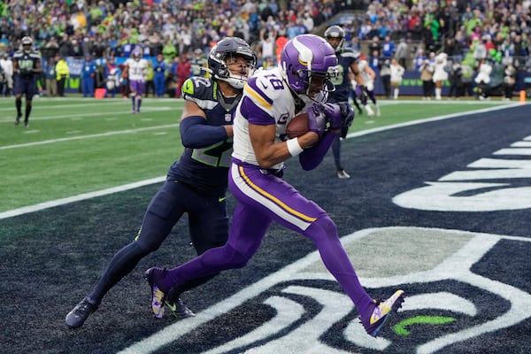 Minnesota Vikings wide receiver Justin Jefferson (18) catches a 14-yard touchdown pass ahead of Seattle Seahawks cornerback Tre Brown (22) during the first half of an NFL football game, Sunday, Dec. 22, 2024, in Seattle. (AP Photo/Stephen Brashear)