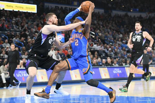 Oklahoma City Thunder guard Shai Gilgeous-Alexander, right, drives past Utah Jazz guard Svi Mykhailiuk, left, during the first half of an NBA basketball game, Wednesday, Jan. 22, 2025, in Oklahoma City. (AP Photo/Kyle Phillips)