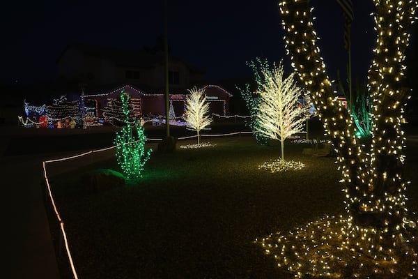 Trees are decorated with holiday lights in a neighborhood in Mesa, Ariz., Thursday, Dec. 12, 2024, in Mesa, Ariz. (AP Photo/Ross Franklin)