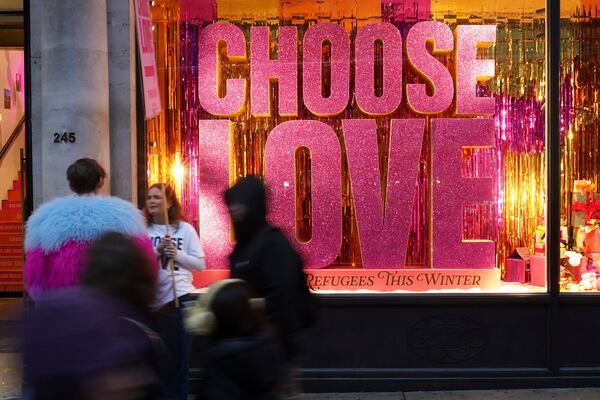 Christmas shoppers pass a sign in a shop window 'Choose Love' in central London, Friday, Dec. 13, 2024, Britain's economy unexpectedly shrank by 0.1 percent in October, The Office for National Statistics stated in figures released Friday. (AP Photo/Alberto Pezzali)