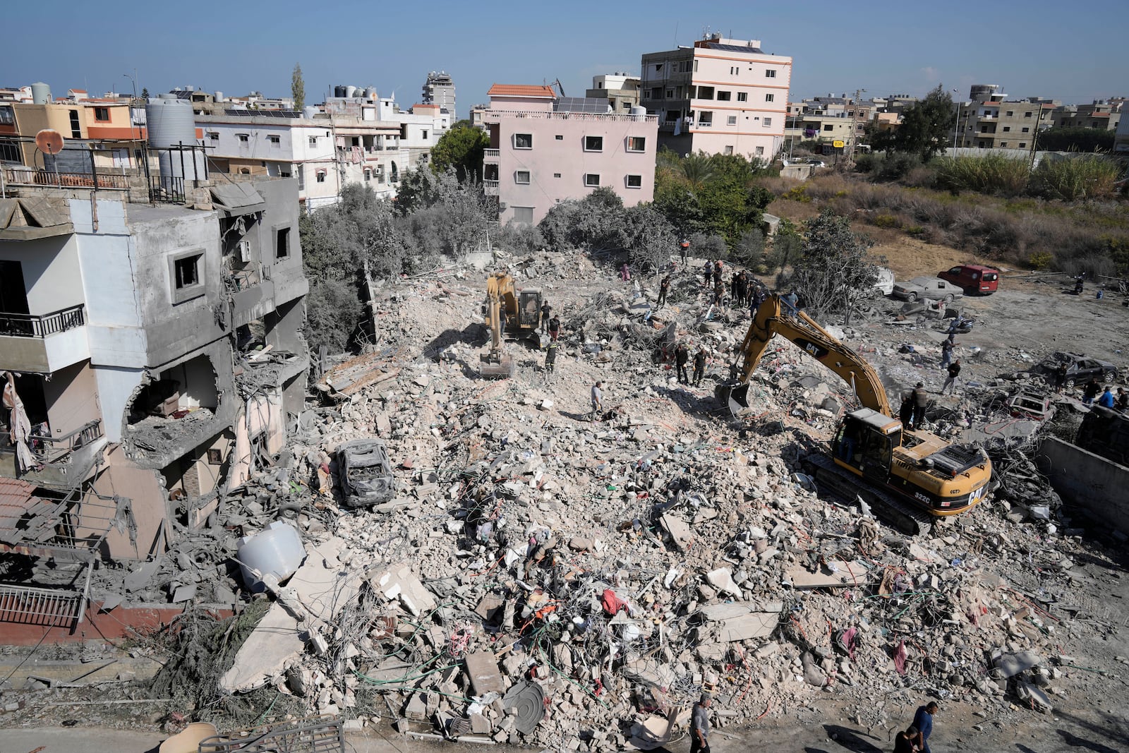 Rescue workers use excavators to remove the rubble of a destroyed building that was hit Tuesday night in an Israeli airstrike, as they search for victims in Sarafand, south Lebanon, Wednesday, Oct. 30, 2024. (AP Photo/Bilal Hussein)