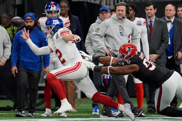 New York Giants quarterback Drew Lock (2) is knocked out of bounds by Atlanta Falcons defensive tackle David Onyemata (90) in the first half of an NFL football game in Atlanta, Sunday, Dec. 22, 2024. (AP Photo/Mike Stewart)