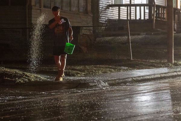 A man spreads salt on 42nd Street near Pacific Street after freezing rain coated surfaces with ice in Omaha, Neb. on Friday, Dec. 13, 2024. (Chris Machian/Omaha World-Herald via AP)