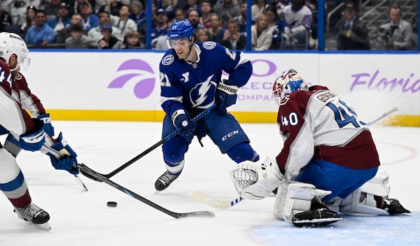 Tampa Bay Lightning center Brayden Point (21) looks to shoot against Colorado Avalanche defenseman Calvin de Haan (44) and goaltender Alexandar Georgiev (40) during the second period period of an NHL hockey game Monday, Nov. 25, 2024, in Tampa, Fla. (AP Photo/Jason Behnken)