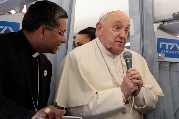 Pope Francis greets the journalists aboard his flight bound for Corsica for his apostolic journey in Ajaccio, Sunday, Dec. 15, 2024. (Remo Casilli/Pool Via AP)