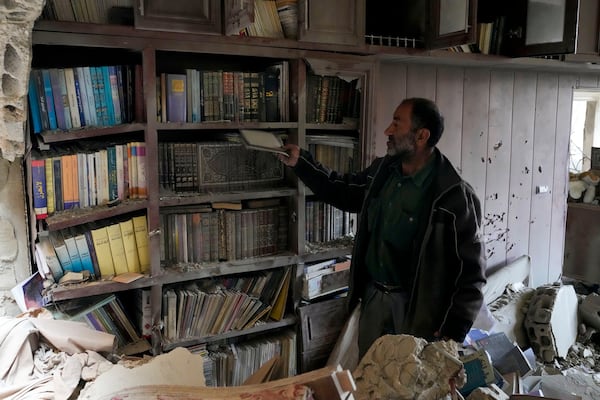 A resident checks a library in a damaged house, in Baalbek, eastern Lebanon, Thursday, Nov. 28, 2024. (AP Photo/Hassan Ammar)