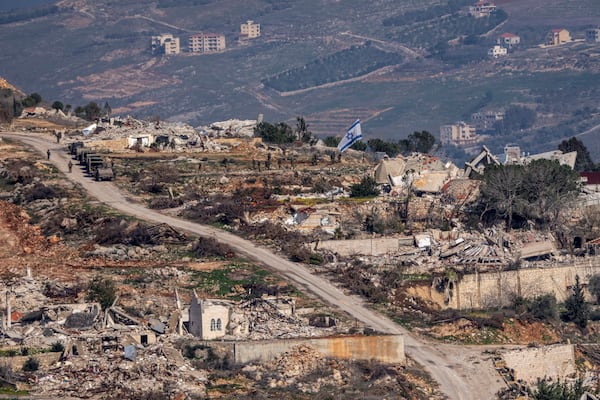 Israeli soldiers stand next to an Israeli flag inside a village in southern Lebanon, as seen form northern Israel, Thursday, Jan. 23, 2025. (AP Photo/Ariel Schalit)