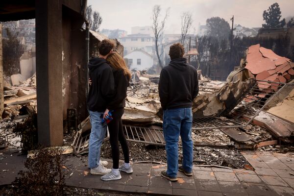 FILE - Residents embrace in front of a fire-ravaged property after the Palisades Fire swept through in the Pacific Palisades neighborhood of Los Angeles, Wednesday, Jan. 8, 2025. (AP Photo/Etienne Laurent, File)