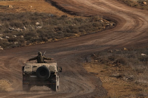 An Israeli soldier stands on an armoured vehicle on the buffer zone after crossing the security fence near the so-called Alpha Line that separates the Israeli-controlled Golan Heights from Syria, viewed from the town of Majdal Shams, Saturday, Dec. 21, 2024. (AP Photo/Matias Delacroix)