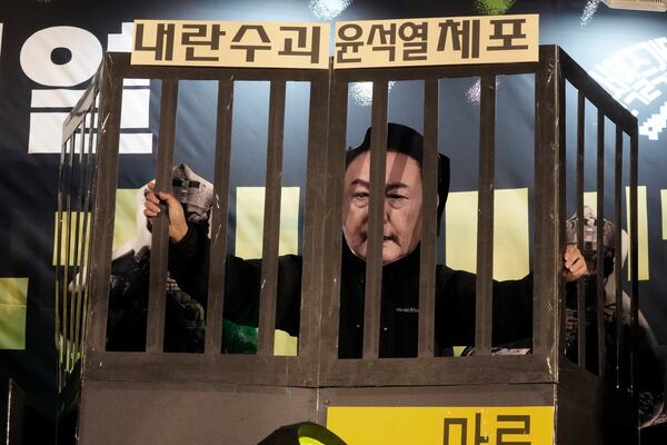 A participant wearing a mask of South Korean President Yoon Suk Yeol performs during a rally to demand his impeachment outside the National Assembly in Seoul, South Korea, Wednesday, Dec. 11, 2024. The signs read "Arrest the rebellion leader Yoon Suk Yeol." (AP Photo/Ahn Young-joon)