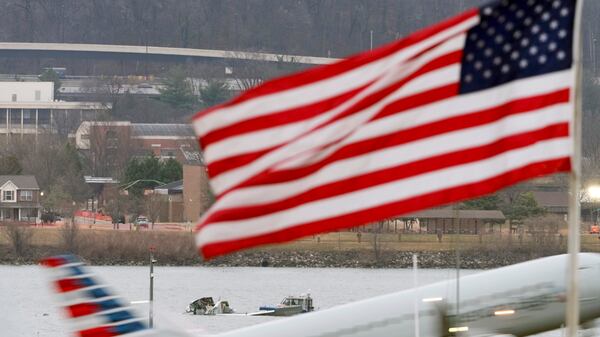 Search efforts are seen around a wreckage site of a deadly midair collision between an American Airlines jet and an Army helicopter, in the Potomac River near Ronald Reagan Washington National Airport, Friday, Jan. 31, 2025, in Arlington, Va., as an American Airlines jet lifts off from the airport, foreground. (AP Photo/Alex Brandon)