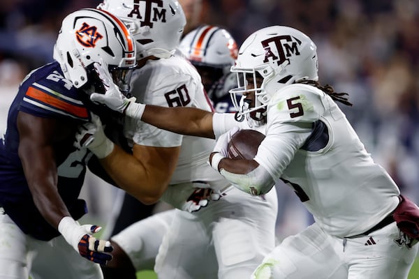 Texas A&M running back Amari Daniels (5) stiff arms Auburn nose tackle Keyron Crawford (24) as he caries the ball during the first half of an NCAA college football game, Saturday, Nov. 23, 2024, in Auburn, Ala. (AP Photo/Butch Dill)