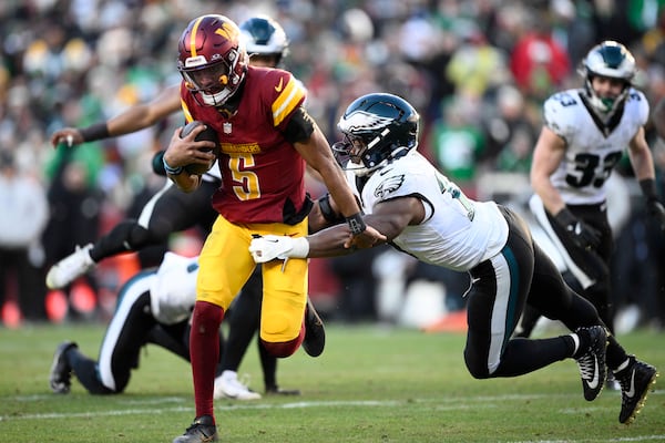 Washington Commanders quarterback Jayden Daniels (5) breaks away from Philadelphia Eagles linebacker Nakobe Dean (17) and runs with the ball during the second half of an NFL football game, Sunday, Dec. 22, 2024, in Landover, Md. (AP Photo/Nick Wass)