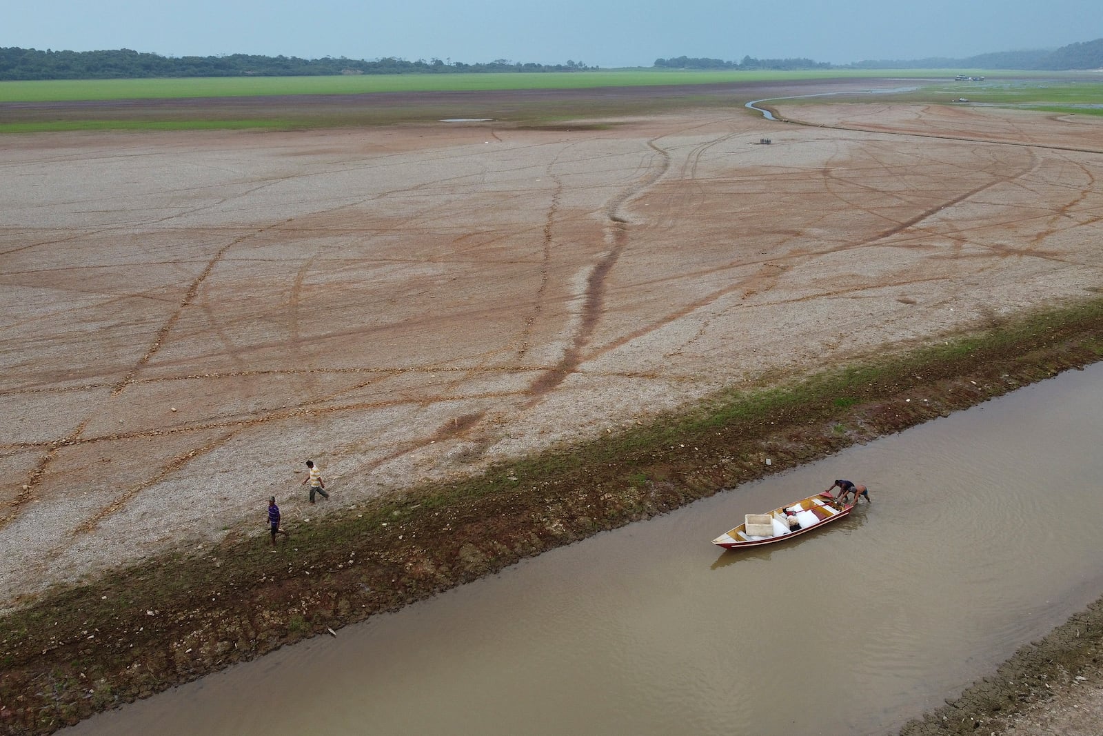 FILE - Fishermen push a boat in the Aleixo Lake amid a drought in Manaus, Amazonas state, Brazil, Sept. 24, 2024. (AP Photo/Edmar Barros, File)