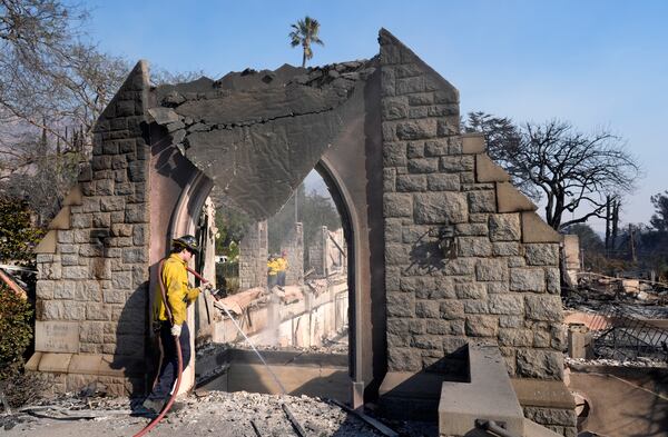 A firefighter hoses down the charred remains of St. Mark's Episcopal Church after it was destroyed by the Eaton Fire, Friday, Jan. 10, 2025, in Altadena, Calif. (AP Photo/Chris Pizzello)