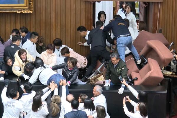 In this image made from video by Taiwan's EBC, lawmakers from the Democratic Progressive Party and members of the Nationalist Party, or Kuomintang, fight for control of the speaker's chair at the Legislature in Taipei, Taiwan on Friday, Dec. 20, 2024. (EBC via AP )