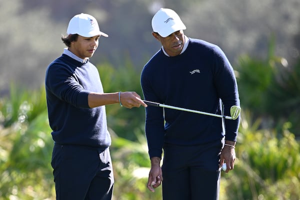 Tiger Woods, right, and his son Charlie Woods discuss their putt on the third green during the first round of the PNC Championship golf tournament, Saturday, Dec. 21, 2024 in Orlando. (AP Photo/Phelan M. Ebenhack)