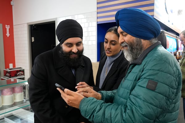 Ishar Gill, left, his sister Verdeen Gill, center and father Jaspal Singh. right, look over congratulatory texts for selling winning the Mega-Million lotto ticket worth an estimated $1.22 billion at the family's store in Cottonwood, Calif., Saturday, Dec. 28, 2024. After three months without anyone winning the top prize in the lottery, the ticket with the winning numbers was drawn Friday night.(AP Photo/Rich Pedroncelli).