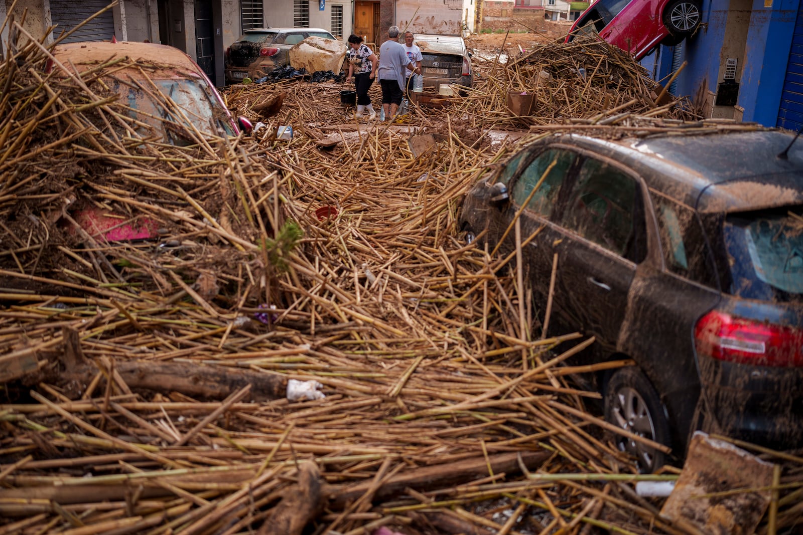 People clean the street in an area affected by floods in Valencia, Spain, Saturday, Nov. 2, 2024. (AP Photo/Manu Fernandez)