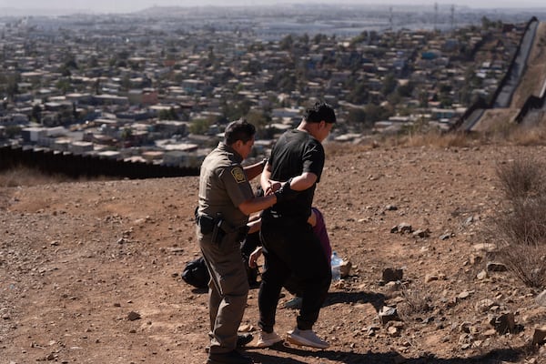 Border Patrol Agent Gutierrez, left, escorts one of four men after the group crossed the border illegally through a gap in two walls separating Mexico from the United States before turning themselves in, Thursday, Jan. 23, 2025, in San Diego. (AP Photo/Gregory Bull)