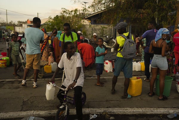 People lineup to collect water Wednesday, Dec. 18, 2024 in the French Indian Ocean island of Mayotte. (AP Photo/Adrienne Surprenant)