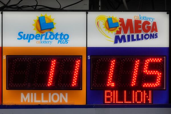 A sign advertising the estimated $1.15 billion Mega Millions jackpot, right, is displayed at Rossi's Deli in San Francisco, Thursday, Dec. 26, 2024. (AP Photo/Jeff Chiu)