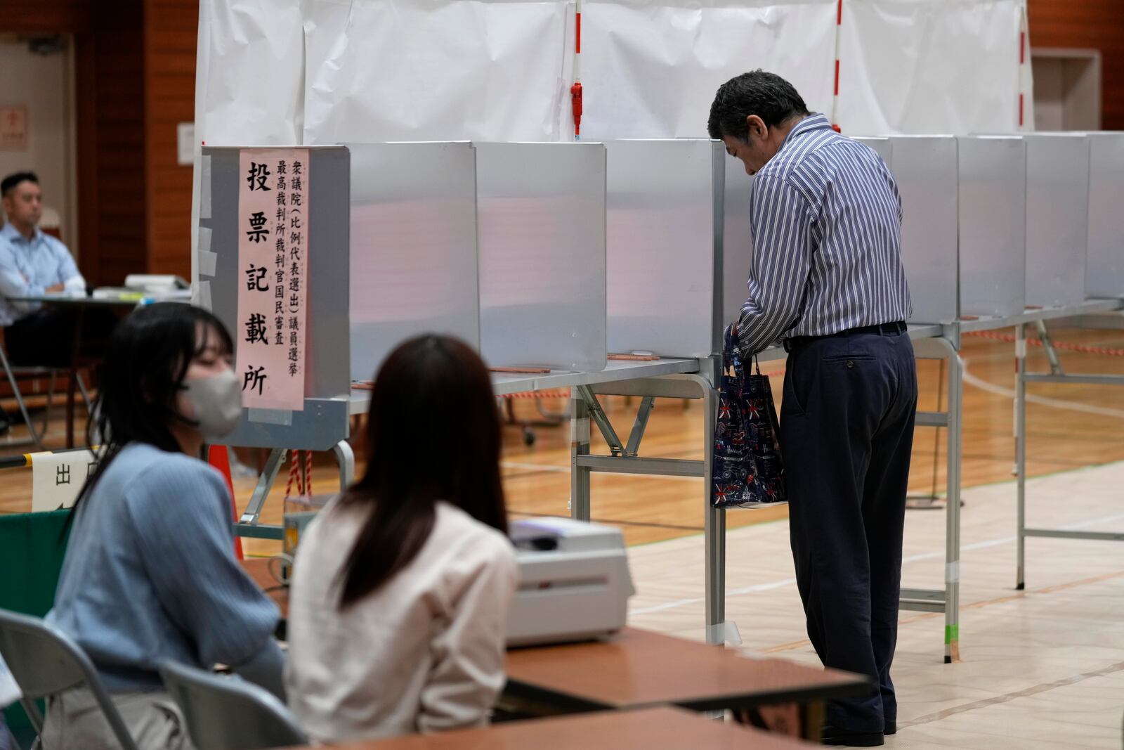 A voter prepares to cast his ballot at a polling station for Japan's lower house election in Tokyo, Japan, Sunday, Oct. 27, 2024. (AP Photo/Hiro Komae)