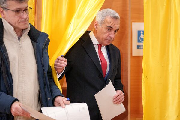 Calin Georgescu, right, an independent candidate for president who came first after the first round of presidential elections, exits a voting booth to cast his vote in the country's parliamentary election in Mogosoaia, Romania, Sunday, Dec. 1, 2024. (AP Photo/Andreea Alexandru)