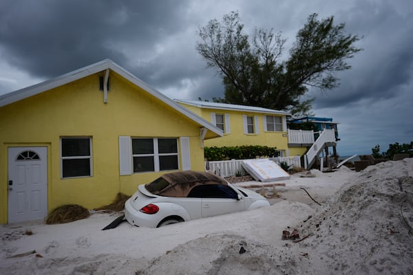 FILE - As Hurricane Milton approaches, a car sits half-buried in sand in Bradenton Beach, Fla., in the aftermath of Hurricane Helene, Oct. 8, 2024. (AP Photo/Rebecca Blackwell, File)