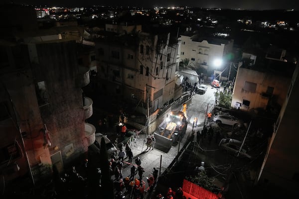 Police and rescue workers gather next to a building hit by a rocket fired from Lebanon in Shefa-Amr in northern Israel, on Monday, Nov. 18, 2024, killing a woman and injuring several others. (AP Photo/Leo Correa)