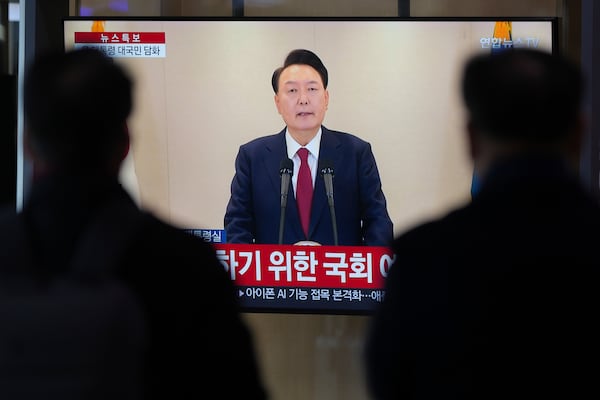 People watch a TV screen showing the live broadcast of South Korean President Yoon Suk Yeol's announcement at the Seoul Railway Station in Seoul, South Korea, Thursday, Dec. 12, 2024. (AP Photo//Lee Jin-man)