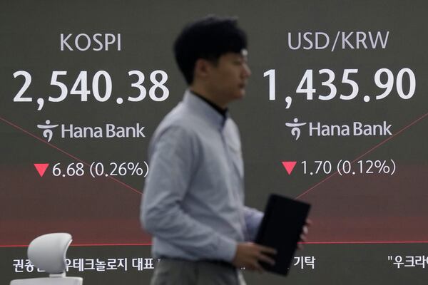 A currency trader passes by a screen showing the Korea Composite Stock Price Index (KOSPI), left, and the foreign exchange rate between U.S. dollar and South Korean won at the foreign exchange dealing room of the KEB Hana Bank headquarters in Seoul, South Korea, Thursday, Jan. 23, 2025. (AP Photo/Ahn Young-joon)