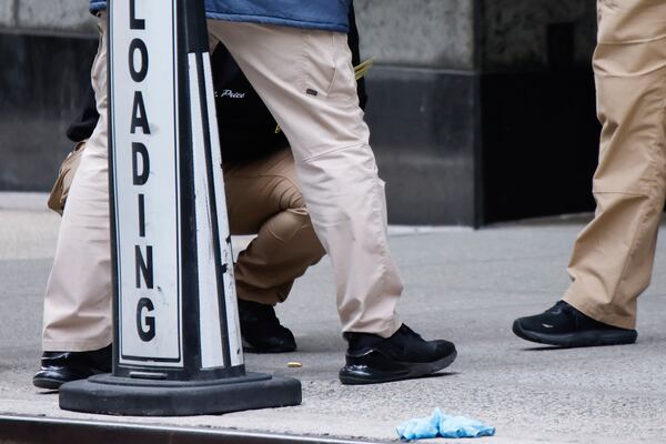 Members of the New York police crime scene unit investigate bullets lying on the sidewalk at the scene outside the Hilton Hotel in midtown Manhattan where Brian Thompson, the CEO of UnitedHealthcare, was fatally shot, Wednesday, Dec. 4, 2024, in New York. (AP Photo/Stefan Jeremiah)