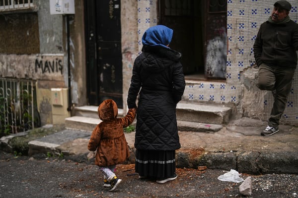 Mehmet Yeralan, 53, a volunteer, talks to a local woman with her child in the Tarlabasi neighborhood in Istanbul, Turkey, Wednesday, Dec. 4, 2024. (AP Photo/Francisco Seco)